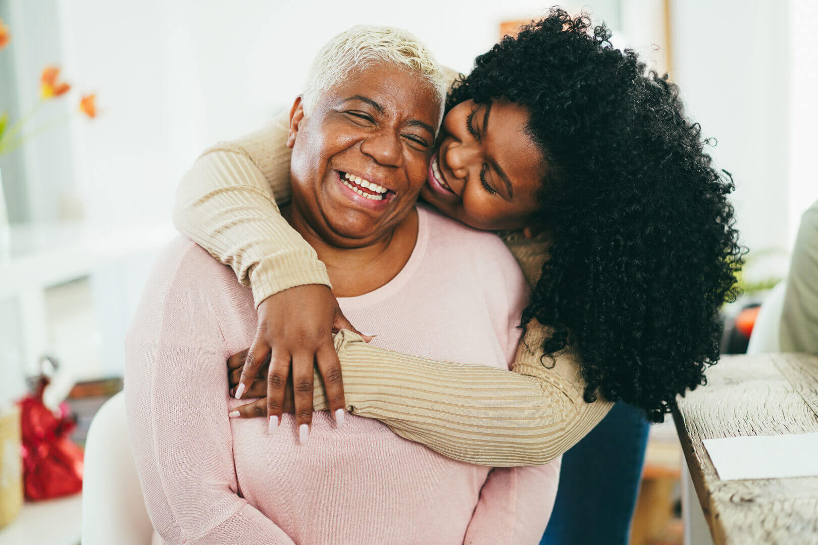 Daughter hugging her smiling mother at home